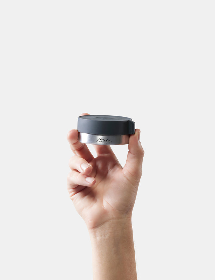 Matador Waterproof Travel Canister - 100ml - hand holding a black and silver container with &