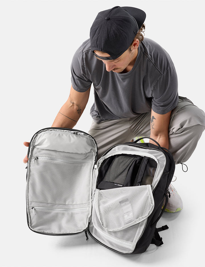 Matador 30L Carry-On Travel Pack in Black - person opening a black and gray backpack on a white background
