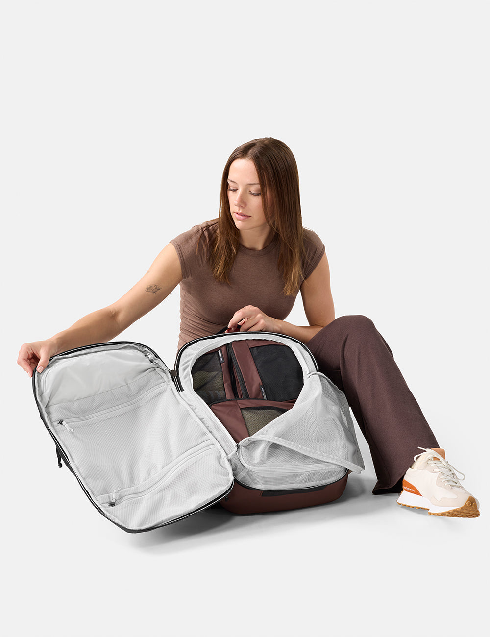 Matador 30L Carry-On Travel Pack in Garnet - woman unpacking a large suitcase on a white background