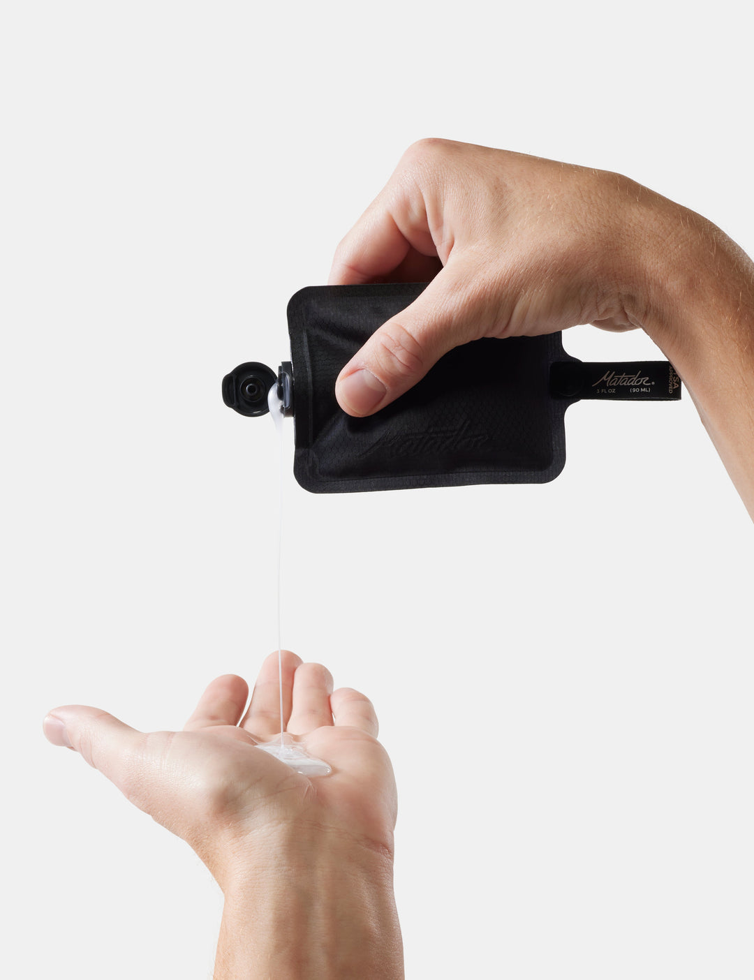 Matador FlatPak™ Toiletry Bottles - 3 Pack (Multi-Colour) - hand using a black travel-sized bottle to dispense liquid soap into another hand on a white background