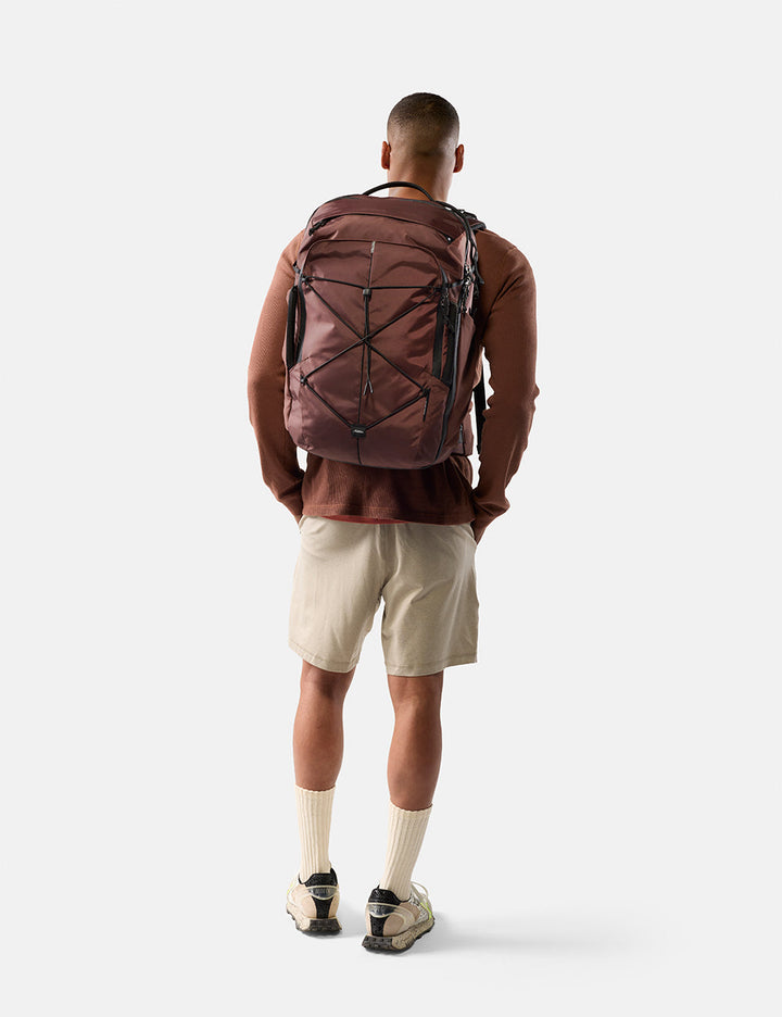 Matador 35L Global Travel Pack in Garnet - person wearing a garnet backpack on a white background