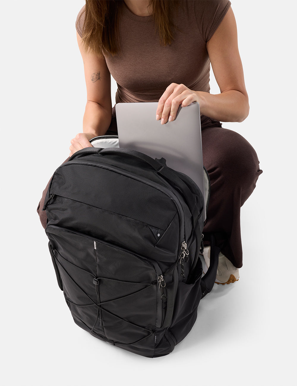 Matador 45L Global Travel Pack in Black - person using a black backpack with a laptop on a white background