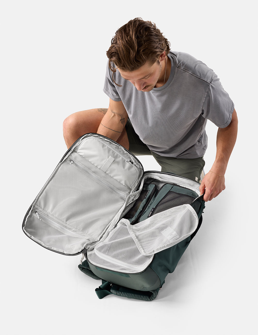 Matador 45L Global Travel Pack in Juniper - person opening a gray backpack on a white background