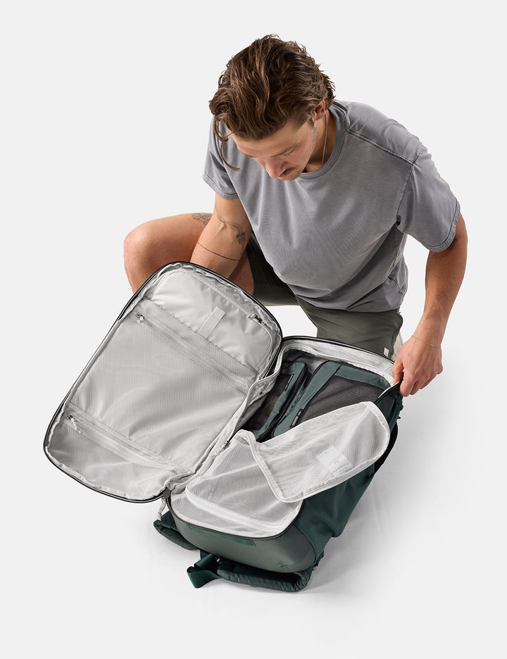 Matador 45L Global Travel Pack in Juniper - person opening a gray backpack on a white background