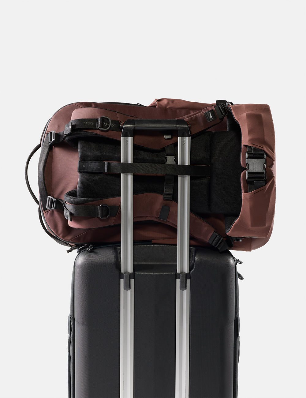 Matador 45L Global Travel Pack in Garnet - garnet backpack on top of a black suitcase with silver handle on a white background