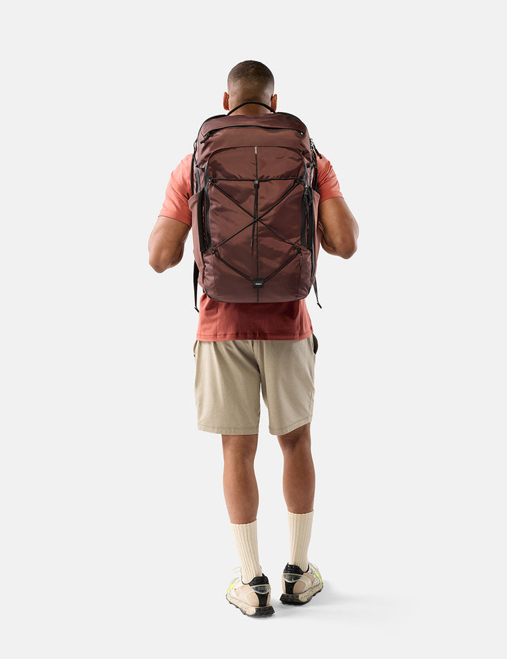 Matador 45L Global Travel Pack in Garnet - person wearing a large garnet backpack on a white background