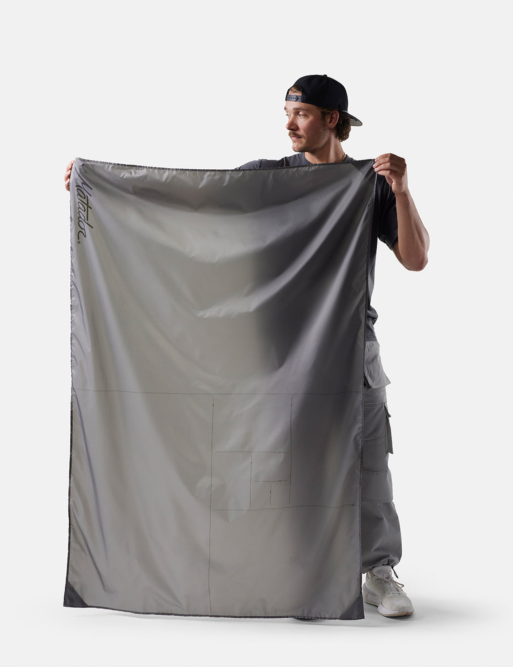 Matador Pocket Blanket™ 4.0 - 160 x 110cm in Ghost Grey - person holding a large gray fabric against a white background