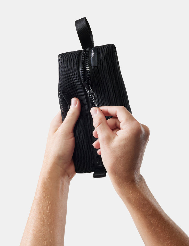 Matador Mesh Organizer Bag Set (3-Pack) - black pouch with a zipper held by hands against a light background
