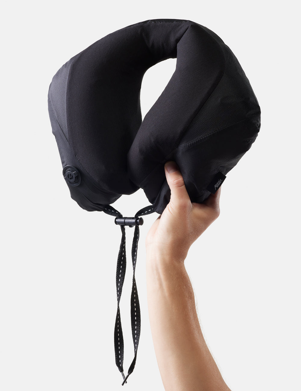 Matador Blackout Travel Pillow - black travel neck pillow held by a hand against a white background