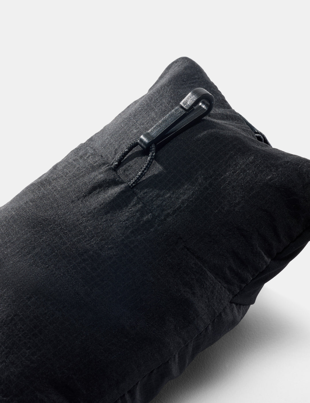 Matador Blackout Travel Pillow - back view of packed up black neck pillow showing small hook