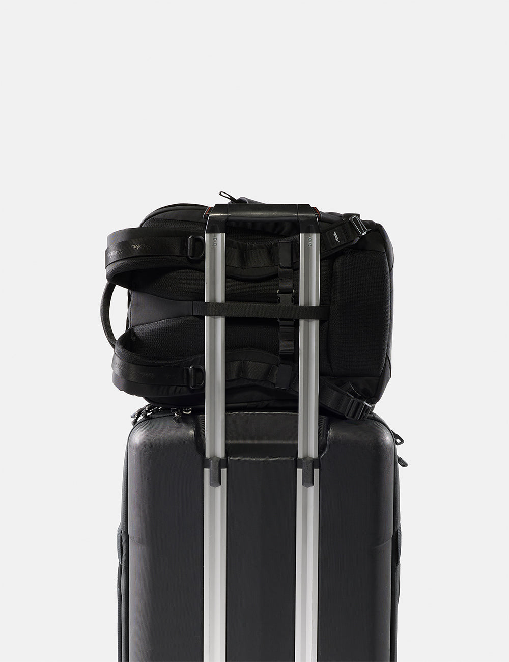 Matador 18L Personal Item Travel Pack in Black - black backpack and suitcase stacked on a white background