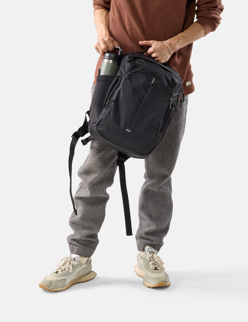 Matador 18L Personal Item Travel Pack in Black - person wearing a black backpack with a plain background