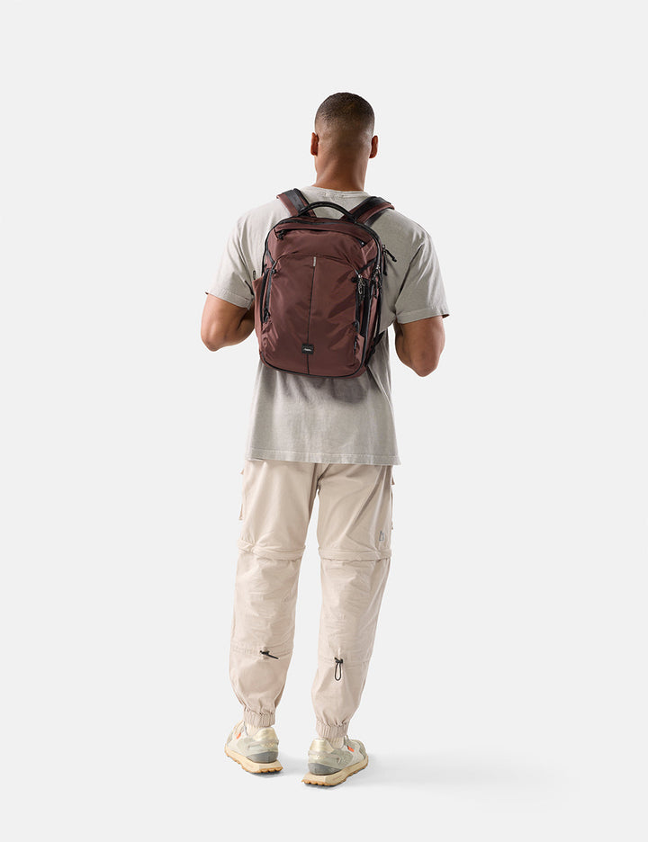 Matador 18L Personal Item Travel Pack in Garnet - person wearing a garnet backpack on a white background