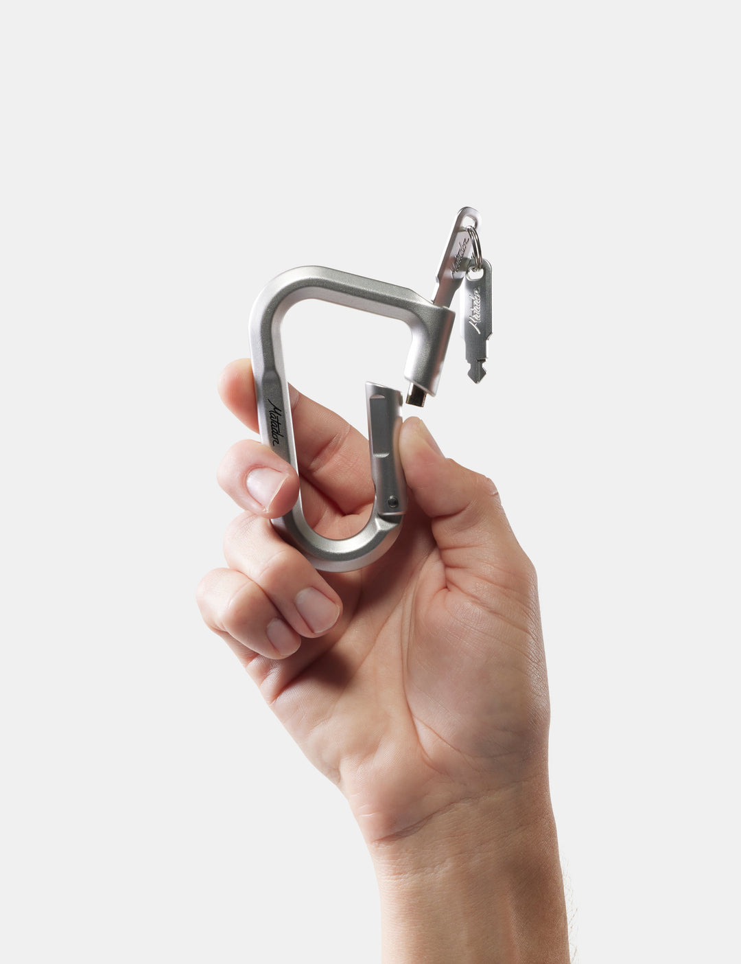 Matador BetaLock in Shadow Green - hand holding a metal carabiner against a white background