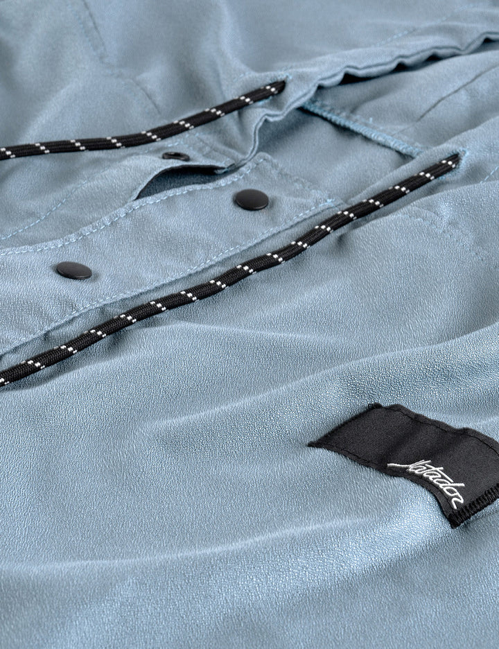 Matador NanoDry™ Packable Towel Poncho in Slate Blue - close-up of a light blue poncho with a brand label on a textured fabric background